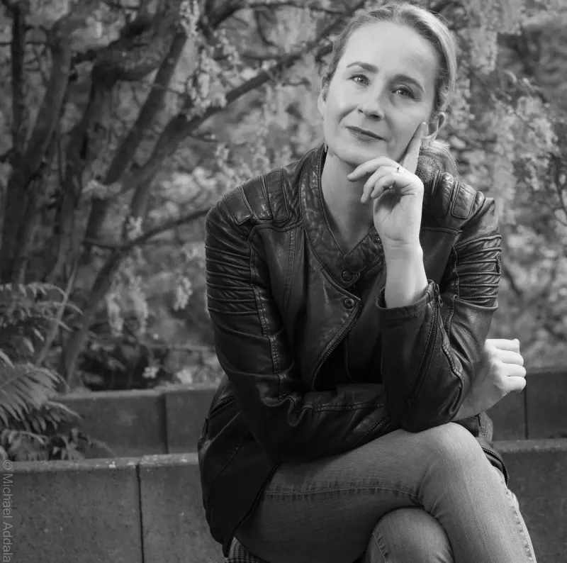 Schwarzweiß-Porträt von Christina Röckelein, sitzend, die Hand am Kinn