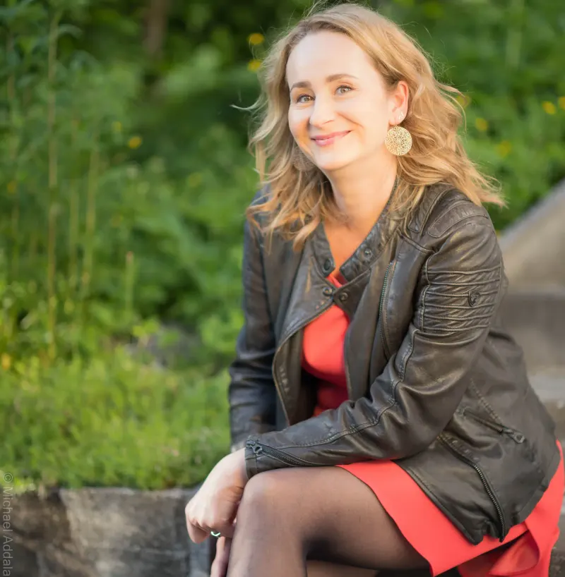 Sitzend auf einer Mauer in Lederjacke und rotem Kleid